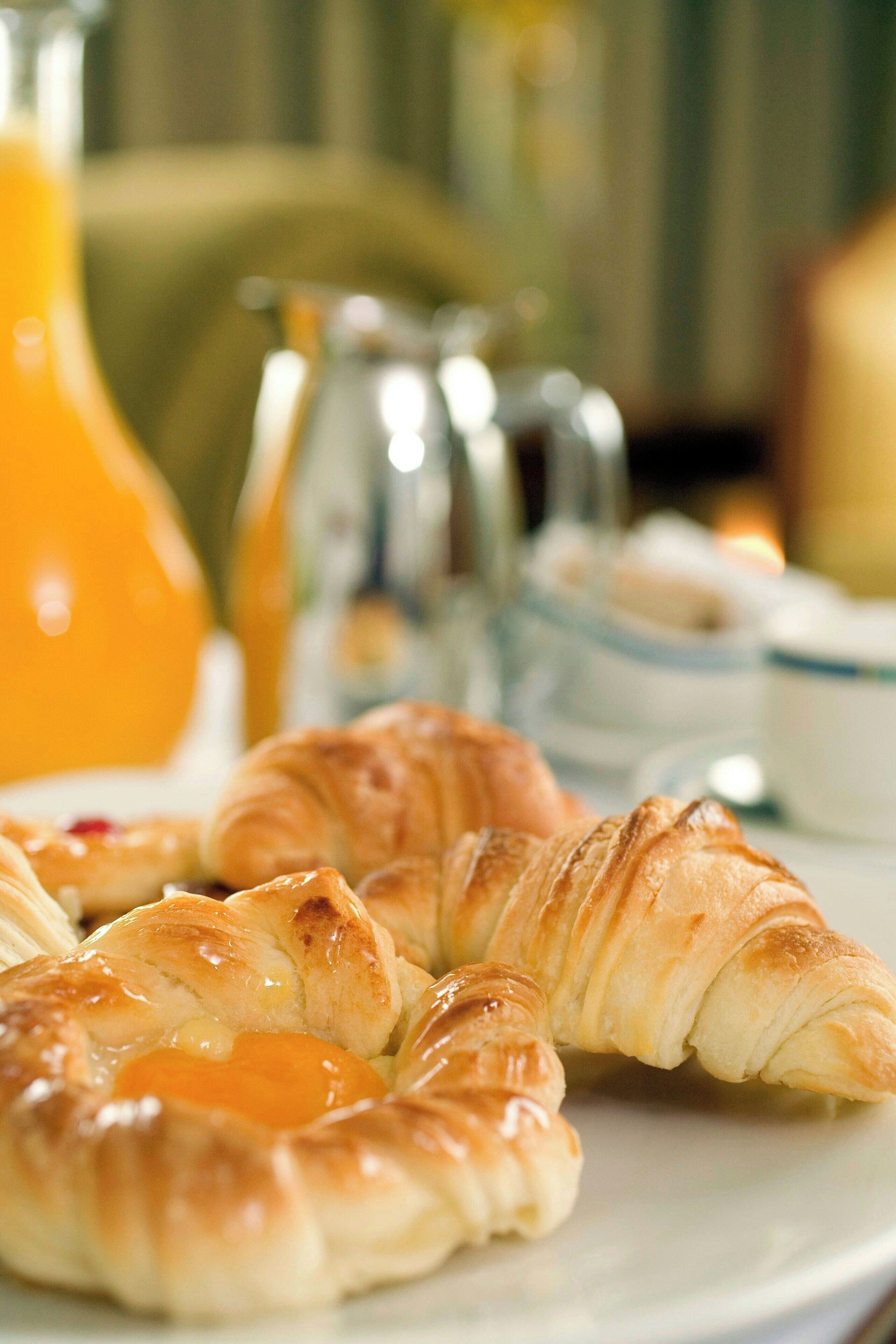 A plate with croissants and a glass of orange juice.