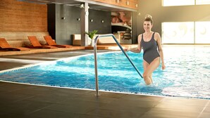 Una piscina interior con cubierta de madera y sillas de descanso.