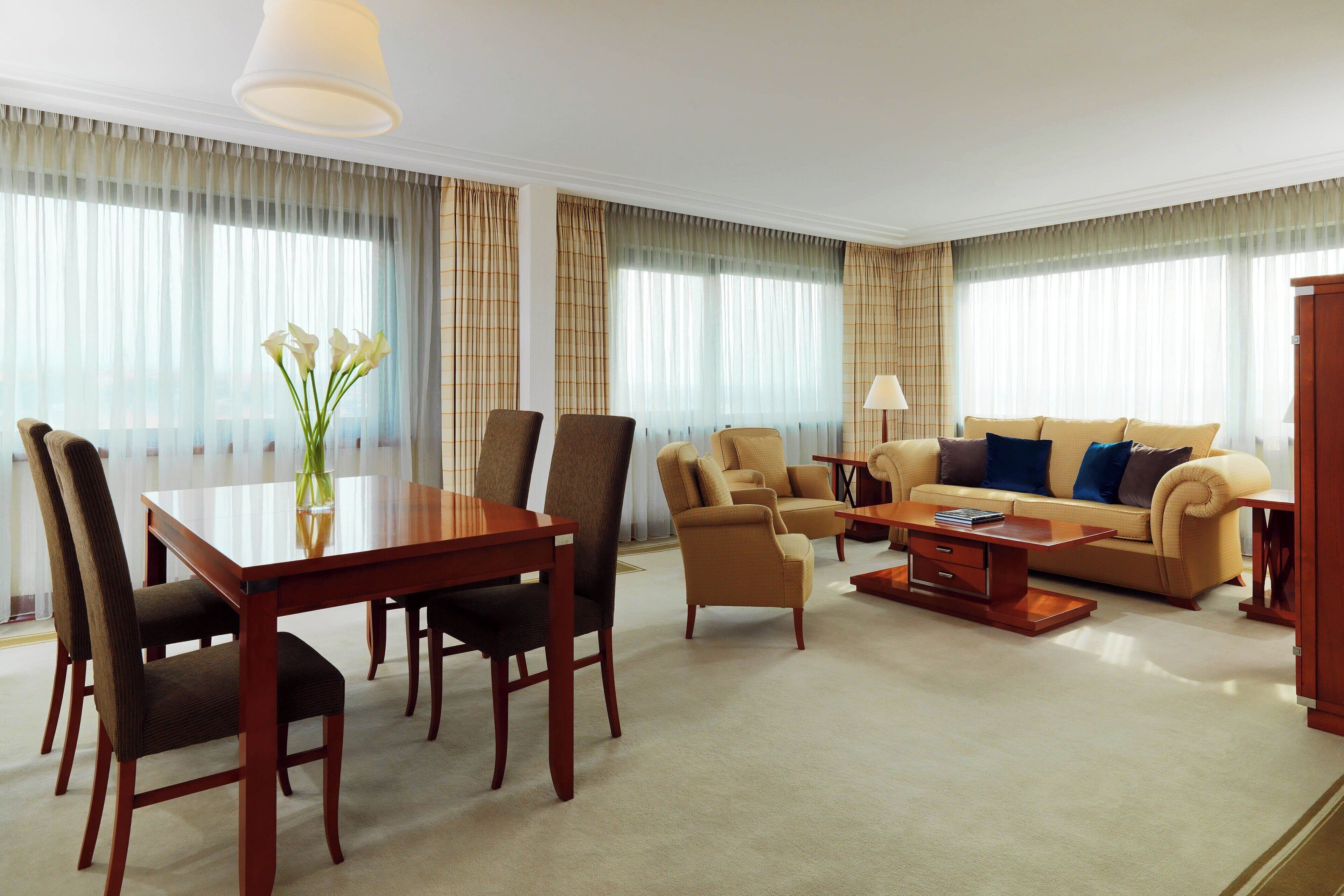 A hotel room with a dining table, chairs, a sofa, and a coffee table.
