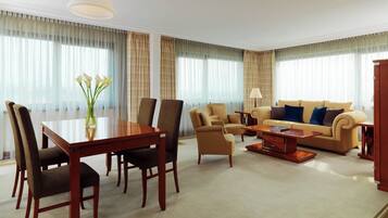 A hotel room with a dining table, chairs, a sofa, and a coffee table.