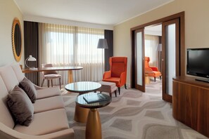 A hotel room with a sofa, two armchairs, a small table, a TV, and a view of another room with a chair and lamp. - The Westin Zagreb (Zagreb)