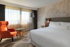 A hotel room with a large bed, an orange armchair, a small round table, and a decorative wall piece. - The Westin Zagreb (Zagreb)