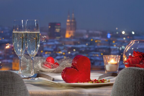 A table set for two with champagne glasses, a heart-shaped dessert, and a candle. - The Westin Zagreb (Zagreb)