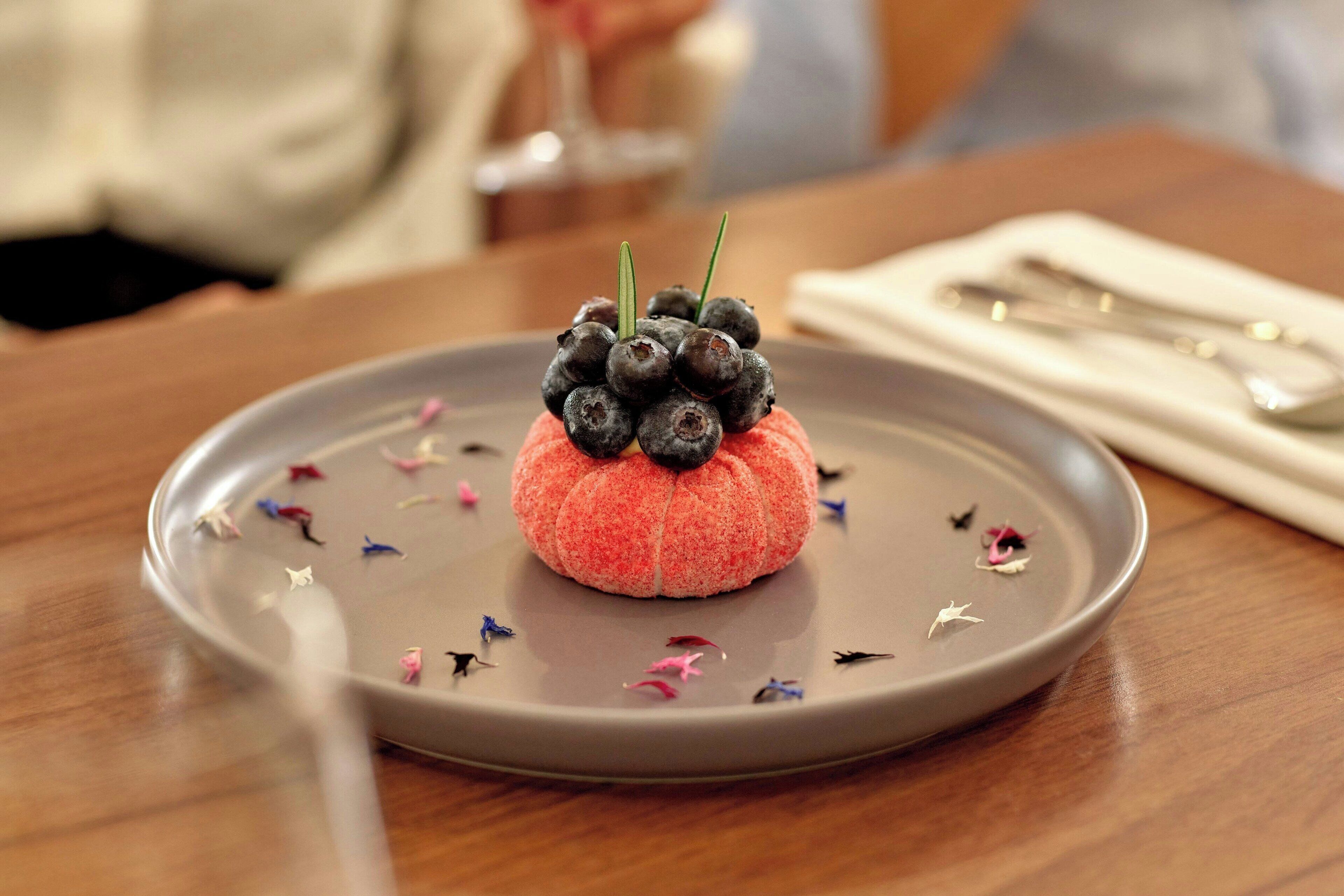 Un postre en un plato con cuchara y servilleta sobre una mesa.