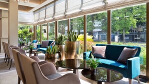 Un vestíbulo de hotel moderno con un ventanal grande, zona de estar y plantas decorativas.