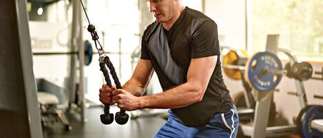 A man exercising with a cable machine in a gym.