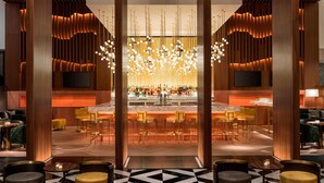 A modern bar area with a central bar, multiple seating options, and a large chandelier.