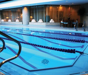 A swimming pool with lane dividers and a poolside area with a table and chairs.
