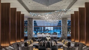A modern lobby with a central seating area, large windows, and a decorative ceiling feature.