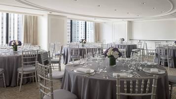 A conference room with round tables, grey chairs, and floral centerpieces.