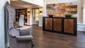 Un hall d’entrée doté d’un parquet en bois foncé, d’un fauteuil à revêtement gris et d’un comptoir d’accueil au design moderne.