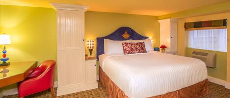 A hotel room with a large bed, a desk with a chair, a nightstand, and a window with a view.