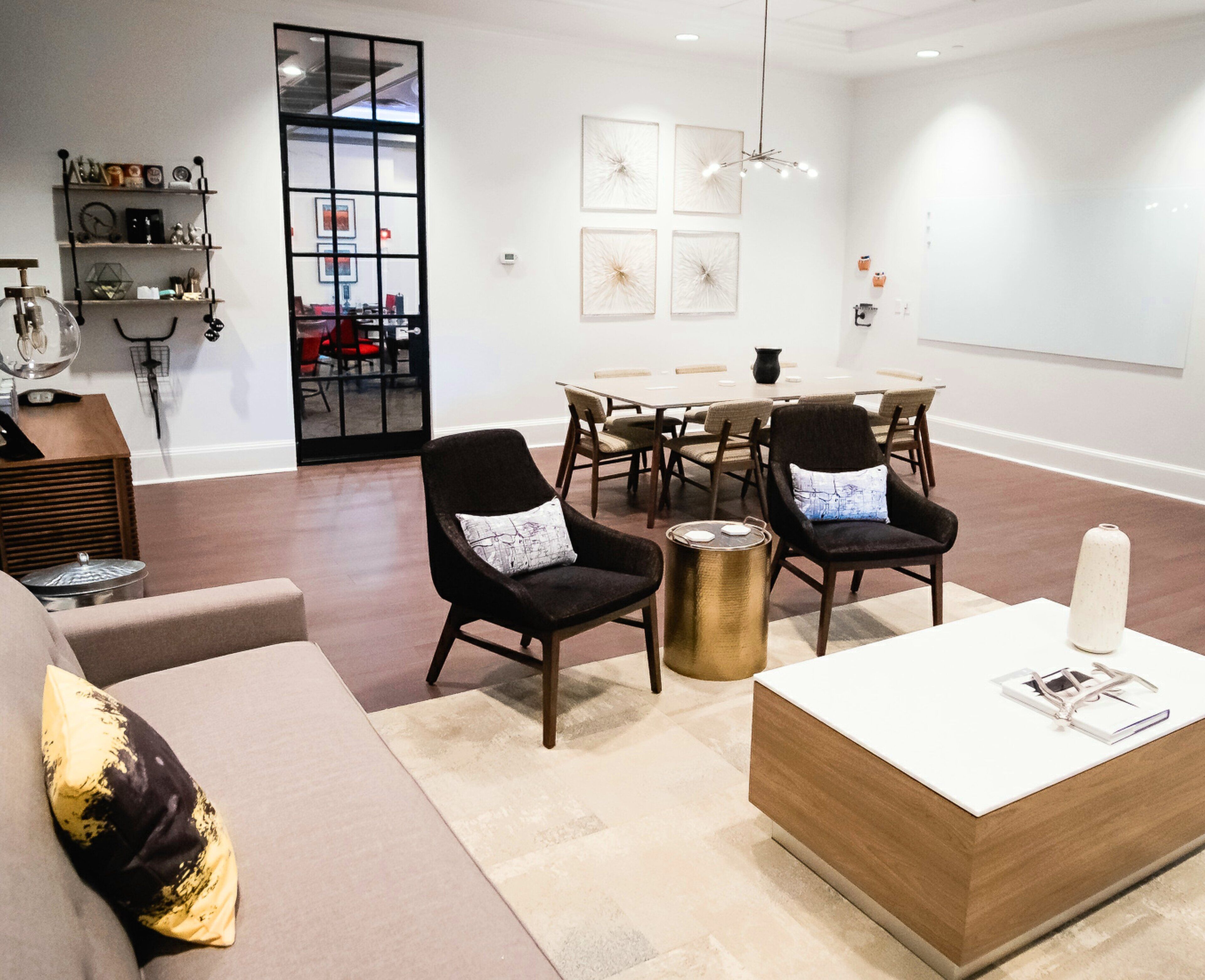 A modern living room with a sofa, chairs, a coffee table, and a dining area with a table and chairs.