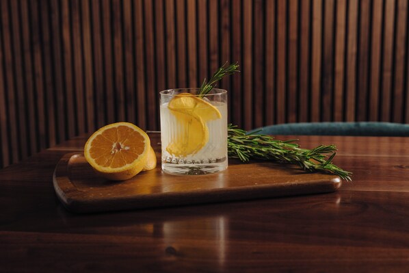 A glass of water with a lemon slice and rosemary on a wooden table. - Crowne Plaza Lansing by IHG (Lansing)