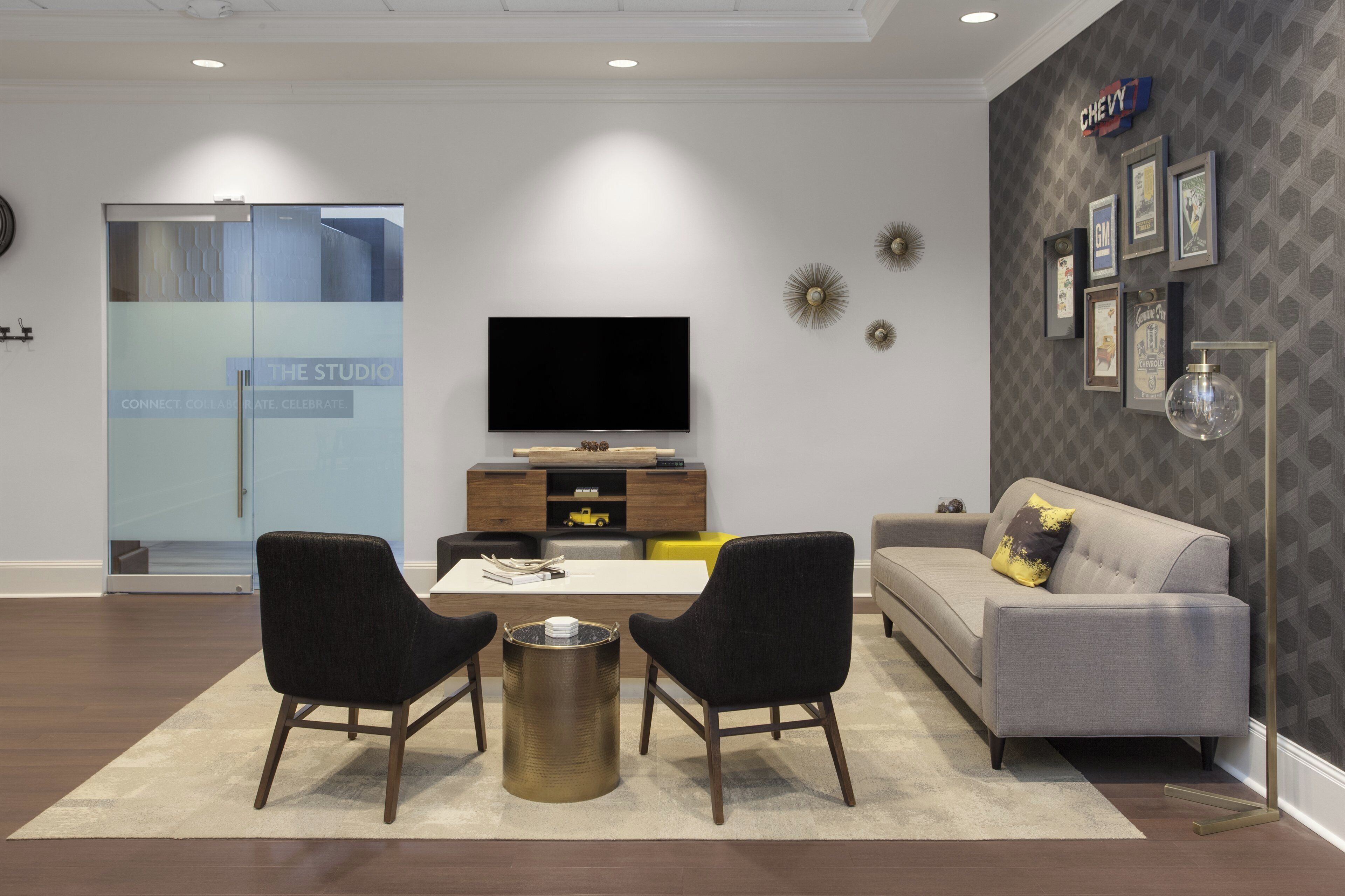 A modern living room with a flat-screen TV, two armchairs, a sofa, and a coffee table.