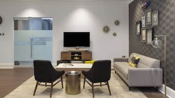 A modern living room with a flat-screen TV, two armchairs, a sofa, and a coffee table.
