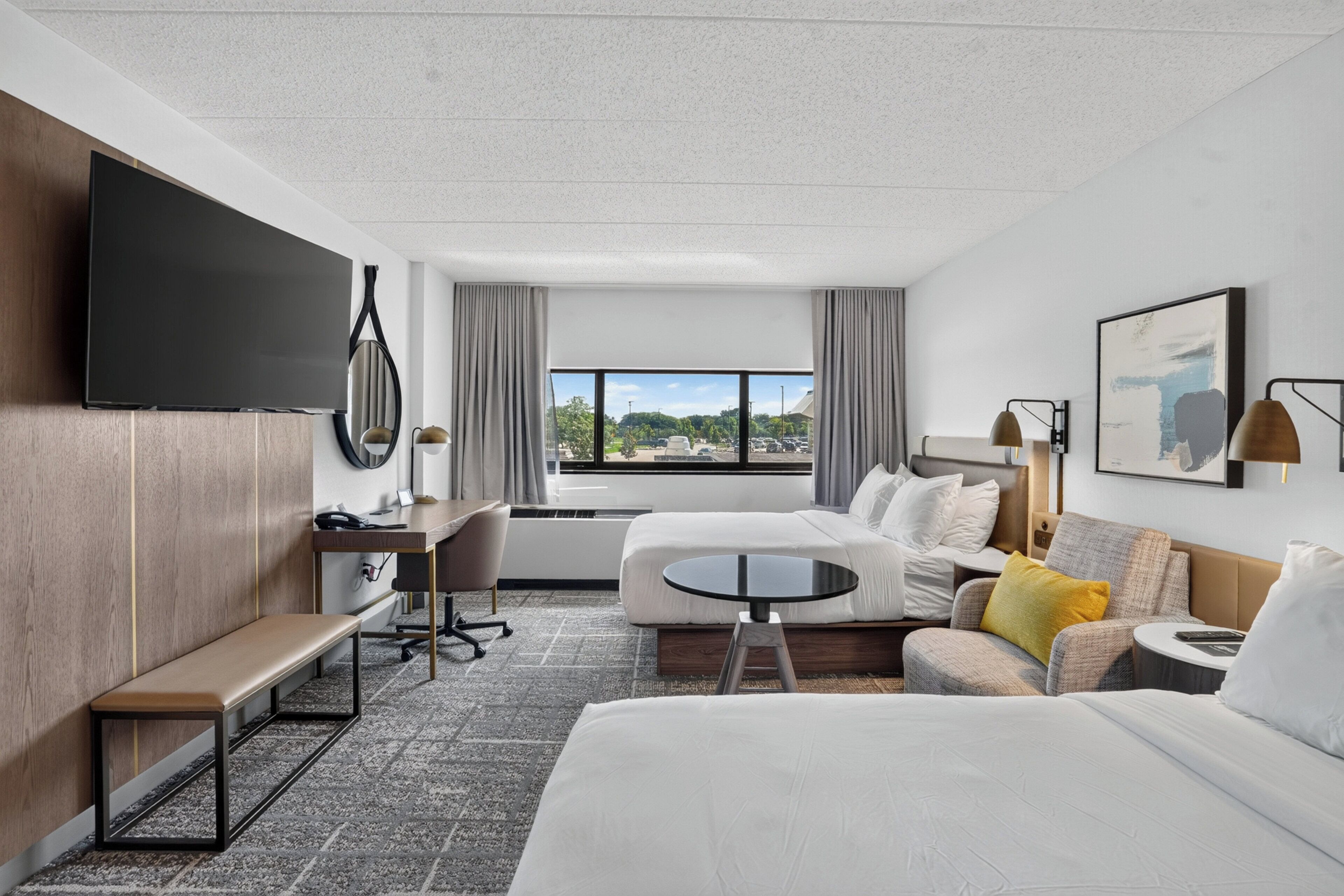Habitación de hotel con cama, escritorio, silla, sofá, televisión y ventana con vistas.