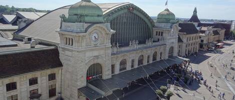 A historic train station with a prominent clock tower, large arched windows, and a green dome.