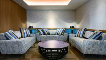 A modern lounge area with patterned sofas and a central coffee table, featuring geometric designs and striped pillows.