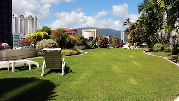 Relax in a serene outdoor space with lounge chairs and a table, surrounded by city views and a mountain range.