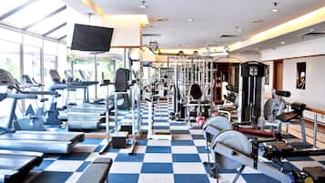 Un gimnasio con cintas de correr, máquinas de pesas y colchonetas de ejercicio.