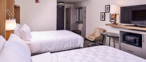 Een hotelkamer met twee bedden, een televisie, een magnetron, een stoel en een kleine tafel.