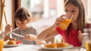 Two children eating breakfast at a table with plates of food and drinks. - Holiday Inn Detroit Northwest - Livonia by IHG (Livonia)