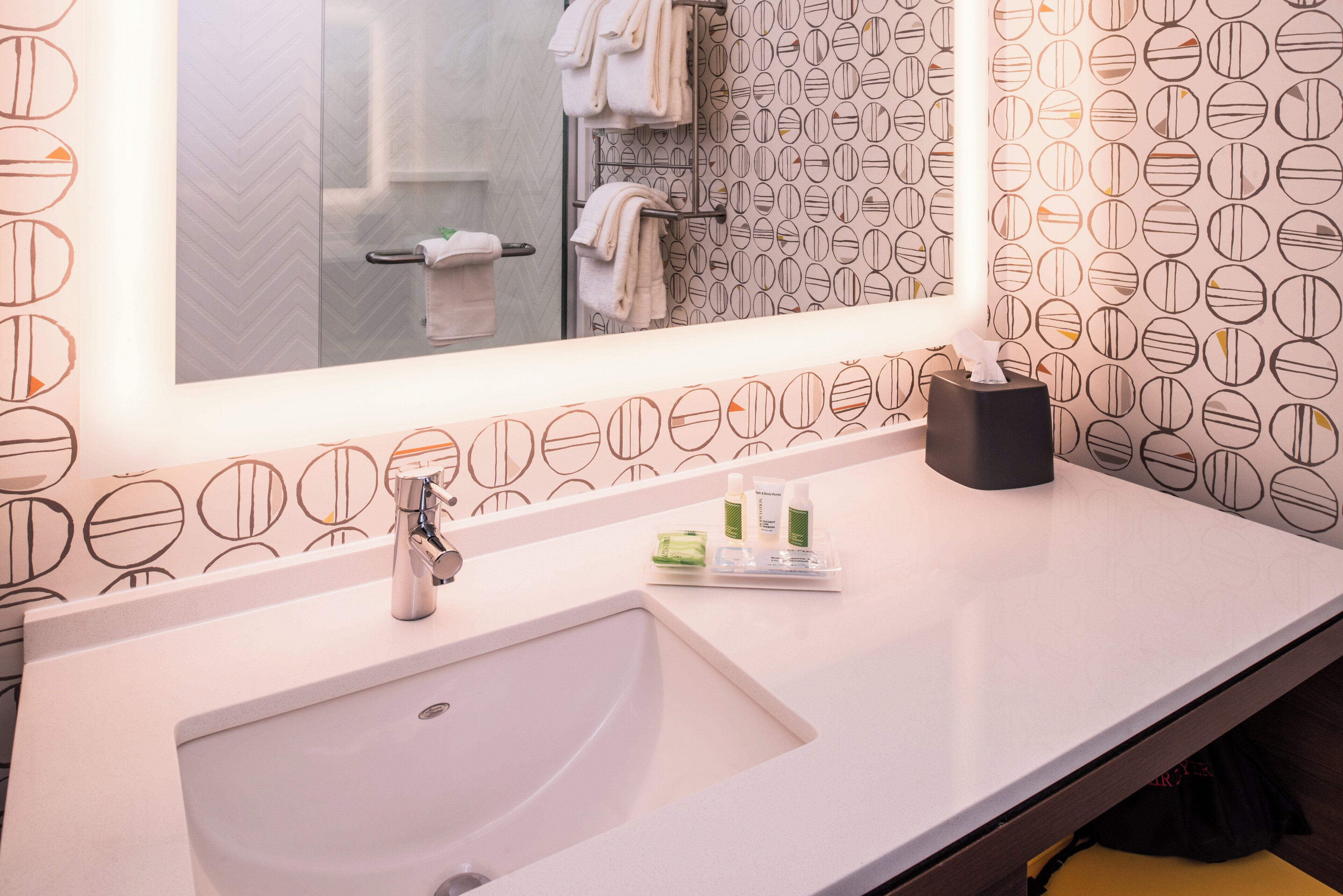 A bathroom with a large mirror, a sink, and a towel rack.