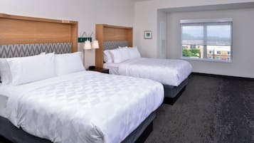 A hotel room with two beds, a large window, and a view of buildings.
