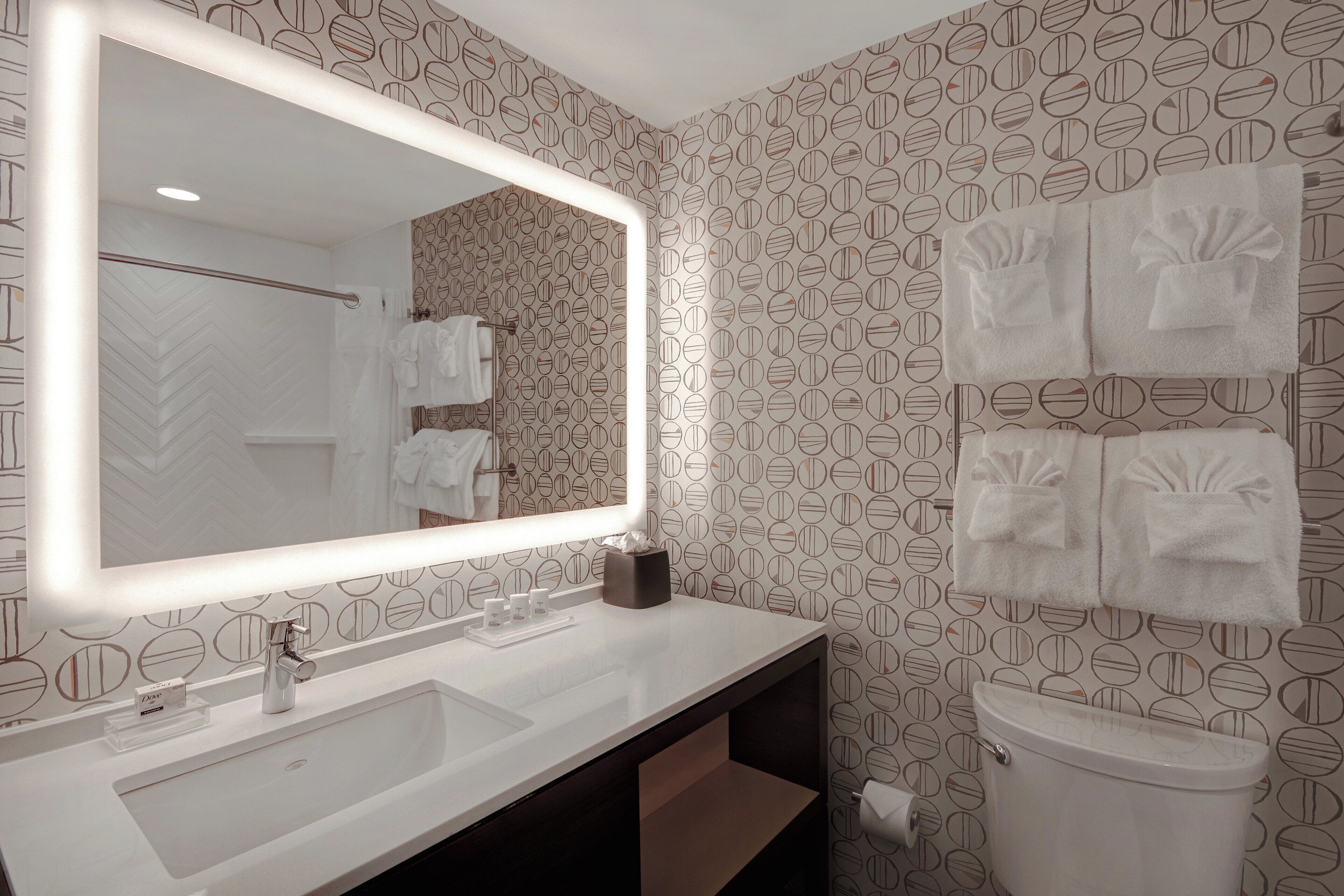 A bathroom with a large mirror, white sink, and toilet.