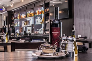 Una zona de bar con una botella de vino, saleros y pimenteros, y un postre en un plato.
