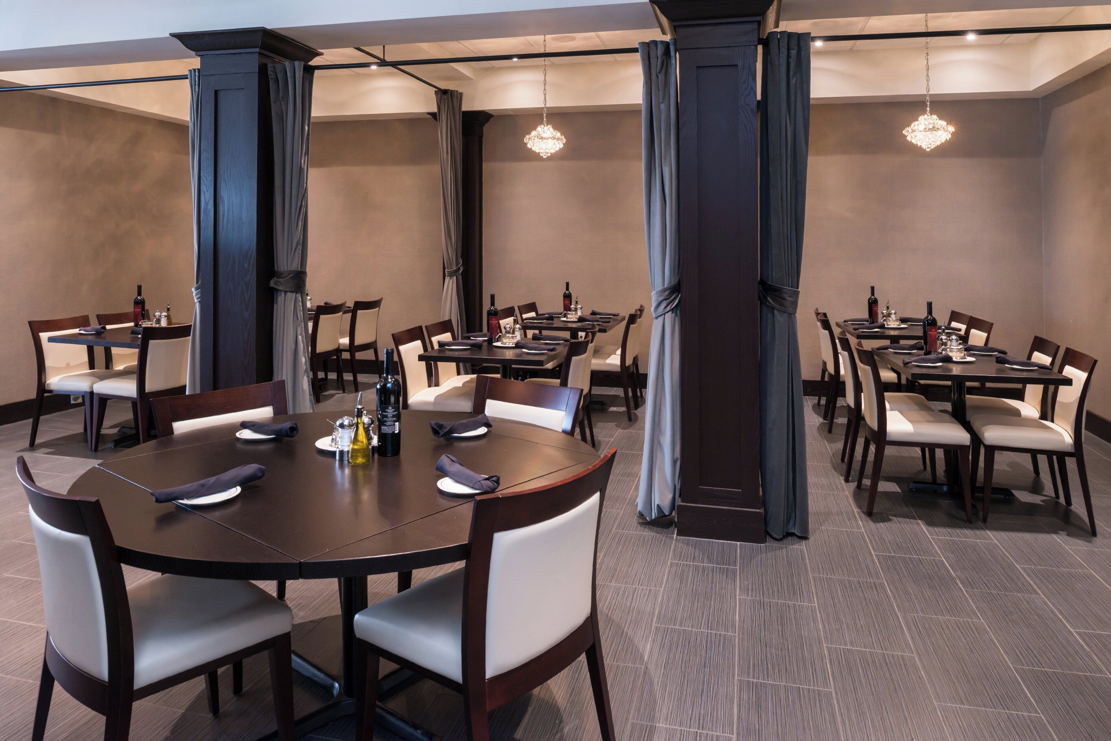 A hotel dining area with multiple tables, chairs, and a chandelier.
