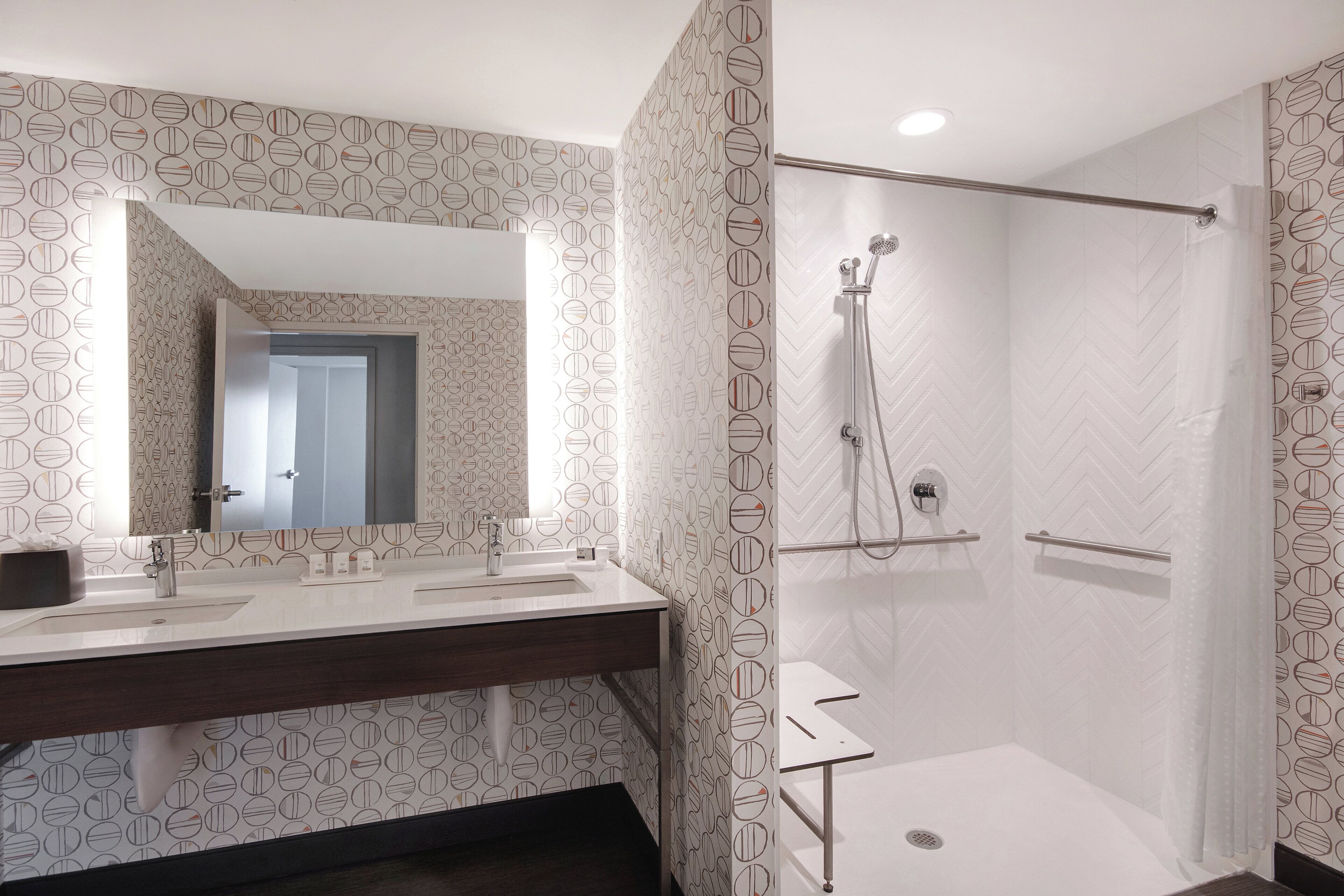 Une salle de bain moderne avec deux lavabos, un grand miroir et un espace douche.