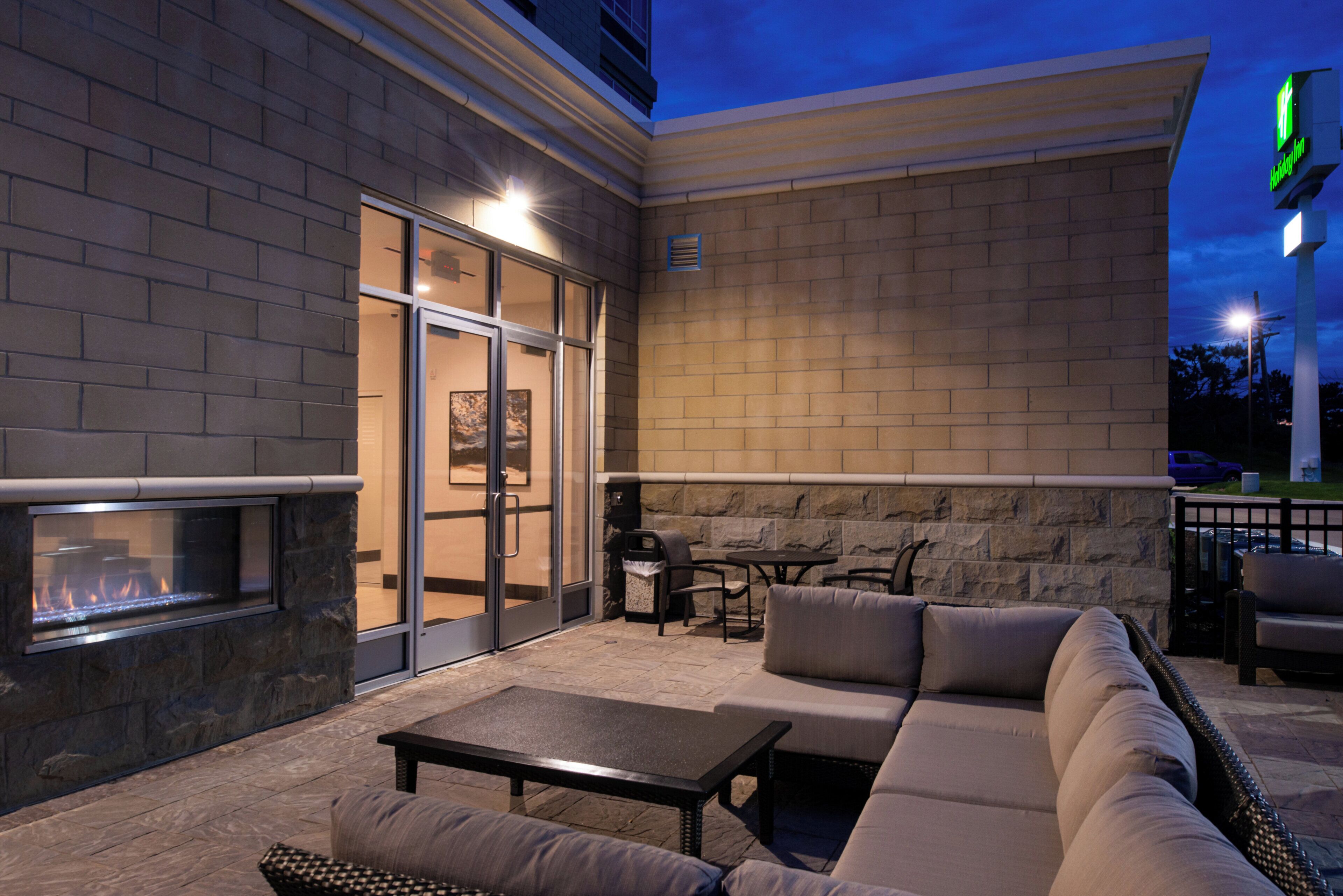 An outdoor patio with a stone fireplace, seating, and a view of the sky.