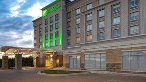A Holiday Inn hotel with a modern brick facade, large windows, and a covered entrance area.