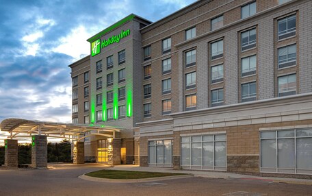 A Holiday Inn hotel with a modern brick facade, large windows, and a covered entrance area.