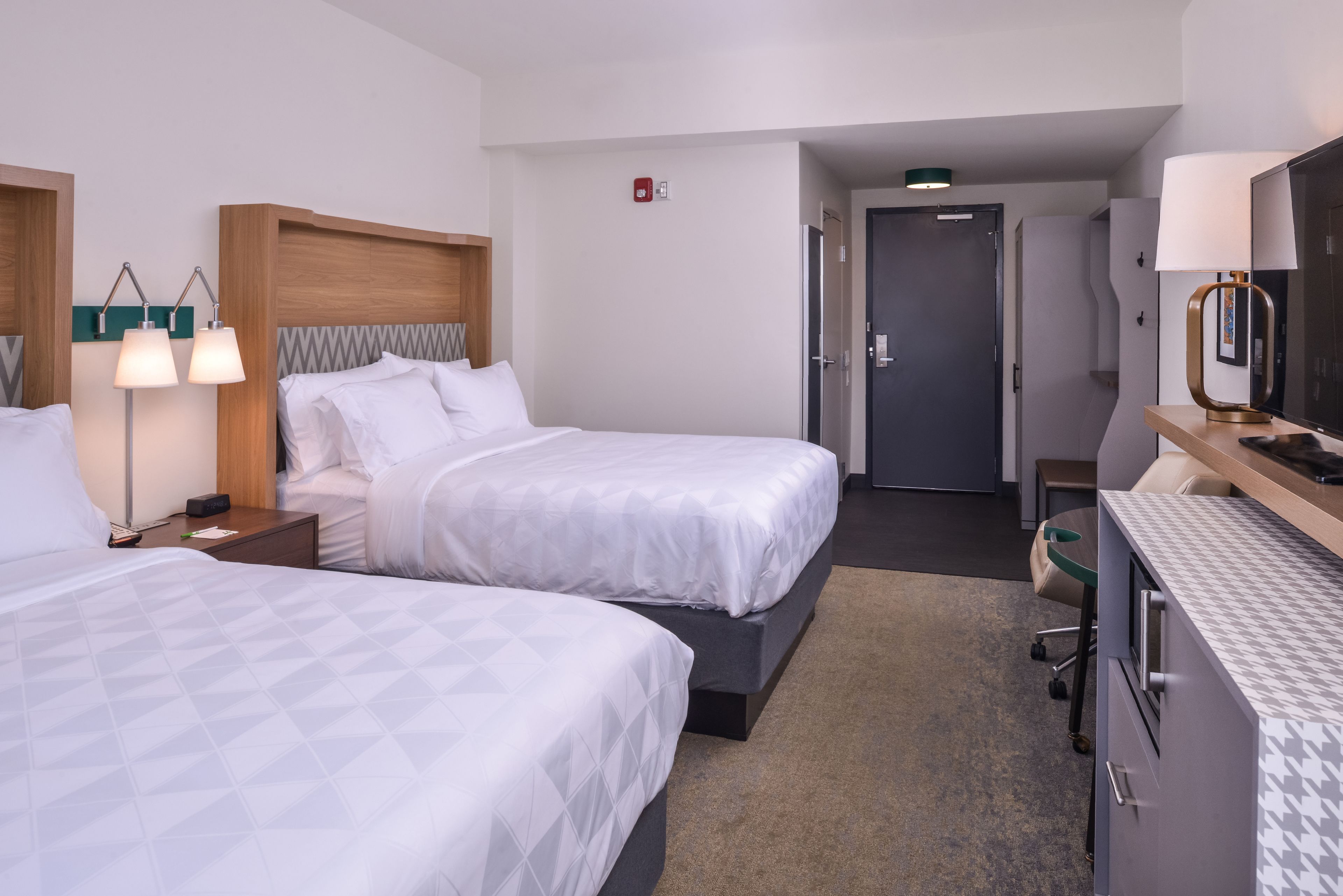Ein Hotelzimmer mit zwei Betten, einem Schreibtisch, einem Stuhl und einem Fernseher.