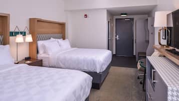 Ein Hotelzimmer mit zwei Betten, einem Schreibtisch, einem Stuhl und einem Fernseher.