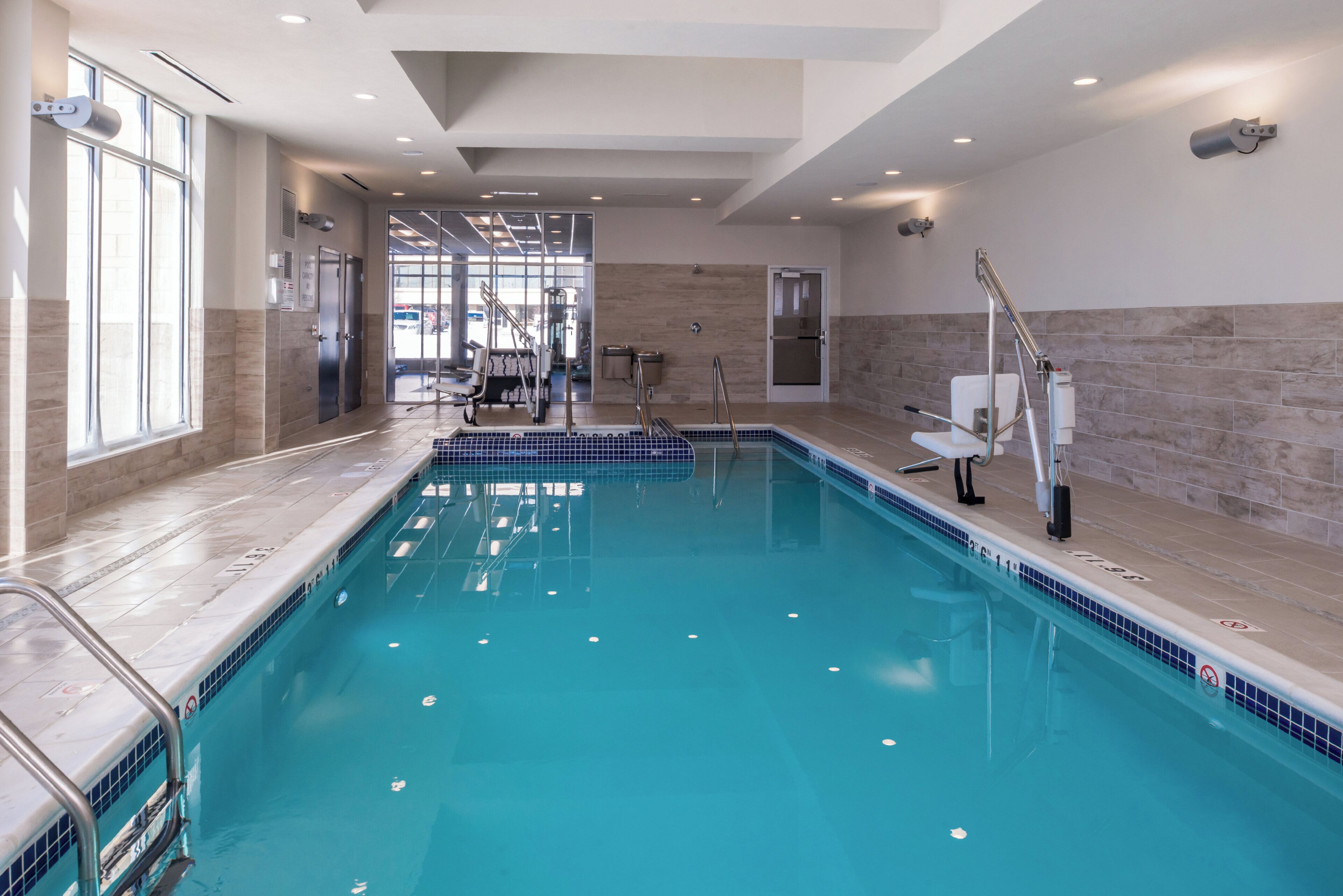 A swimming pool with clear water, a tiled deck, and a modern interior design.