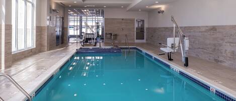 A swimming pool with clear water, a tiled deck, and a modern interior design.