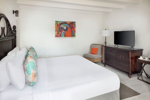 Habitación de hotel con una cama grande, televisión, escritorio con lámpara y un cuadro de colores en la pared.