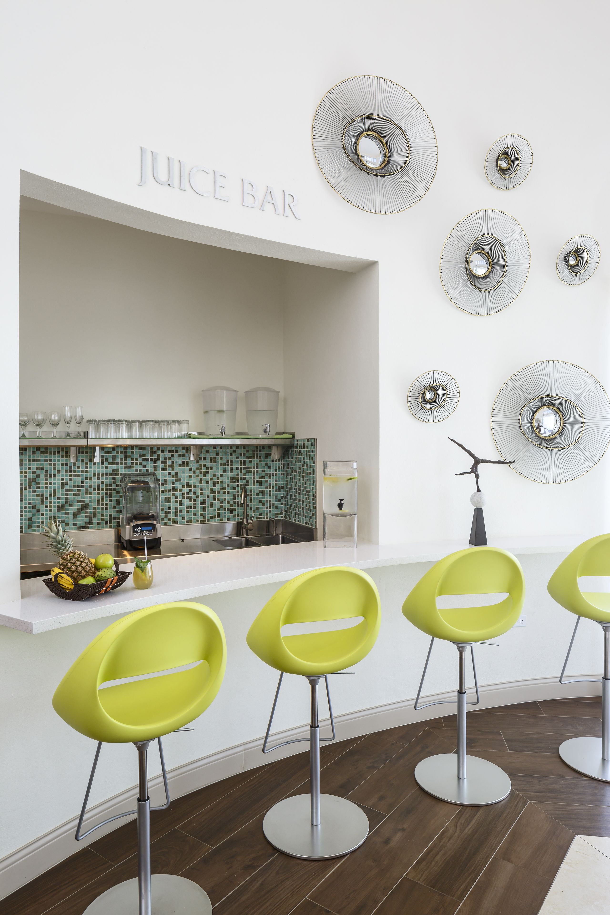 Una cocina moderna con barra de zumos, taburetes y espejos decorativos en la pared.