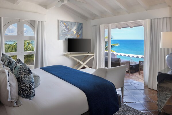 A hotel room with a bed, a TV, a balcony with a view of the ocean, and a seating area with a table and chairs. - Windjammer Landing Resort and Residences (Gros Islet)
