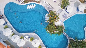 An aerial view of a large, irregularly shaped swimming pool with multiple lanes, surrounded by palm trees and white umbrellas. - Windjammer Landing Resort and Residences (Gros Islet)