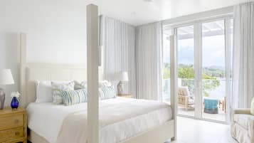 Un dormitorio espacioso con una cama grande, una mesita de noche y vistas al exterior a través de un ventanal corredera.