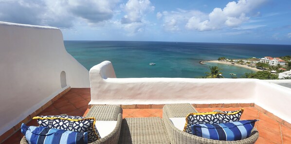 A balcony with wicker furniture and patterned cushions, overlooking a beach and ocean. - Windjammer Landing Resort and Residences (Gros Islet)