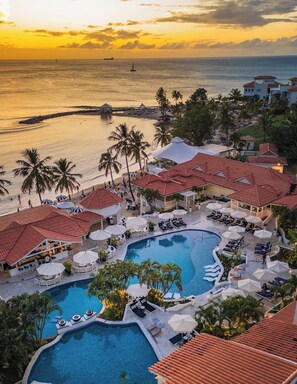 A resort with multiple swimming pools, palm trees, and a view of the ocean at sunset. - Windjammer Landing Resort and Residences (Gros Islet)