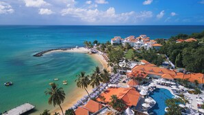Un resort con spiaggia, piscina e molo.
