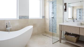 Un baño moderno con una bañera independiente, ducha con mampara de vidrio y tocador con espejo.