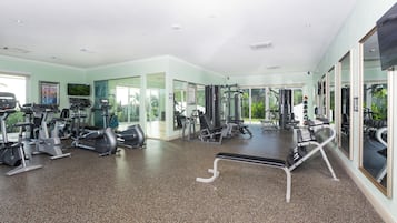 Un gimnasio espacioso con diversa maquinaria de cardio y entrenamiento de fuerza, amplias ventanas y un diseño moderno y limpio.